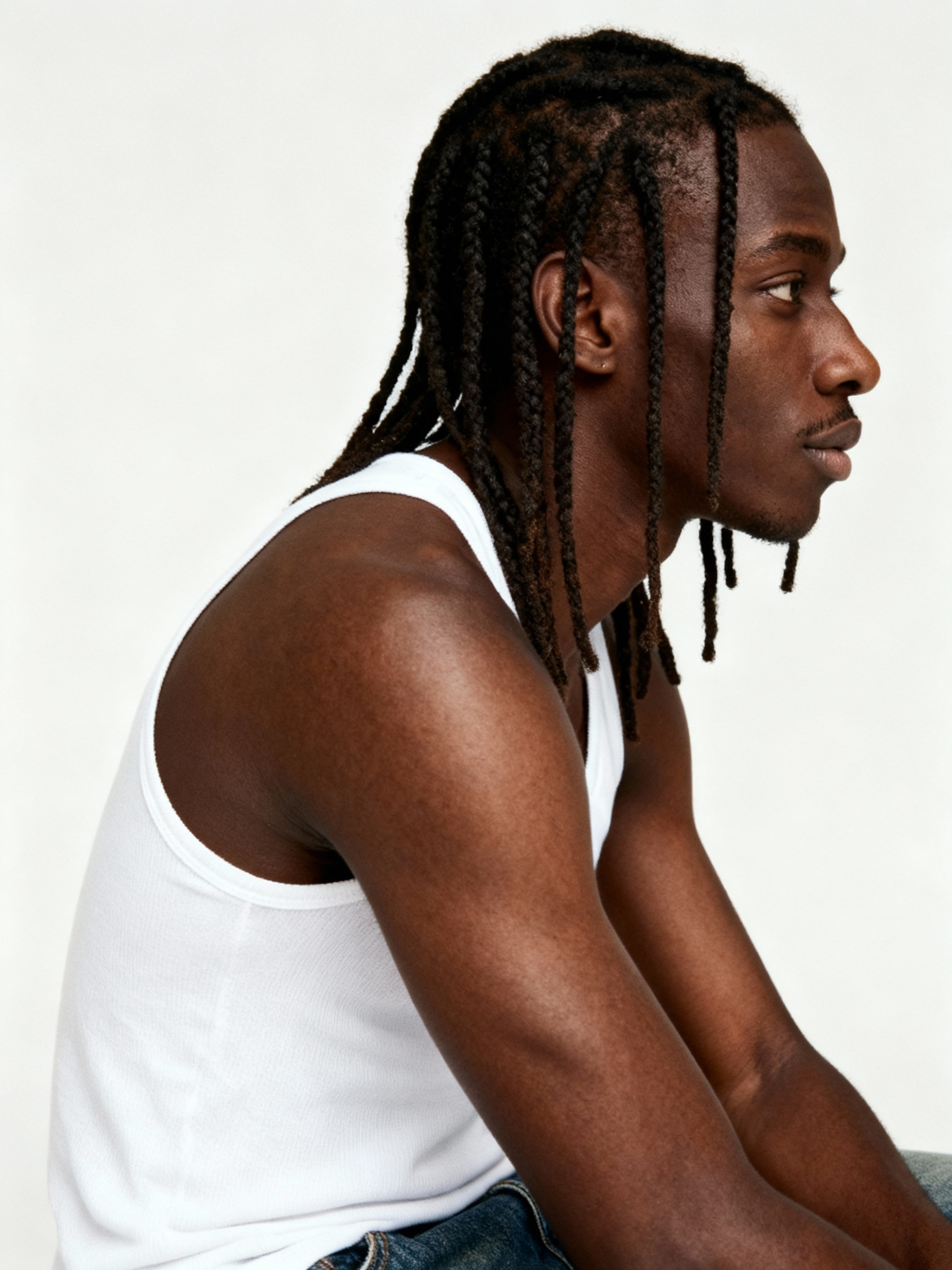 Studio headshot of AI model Jovan with a braided hairstyle. He is wearing a white tank top and has a confident expression, showcasing his look for streetwear and editorial campaigns.